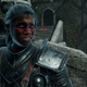 An Elden Ring character with dark skin and red cheeks snarls at the camera while standing outside a stone tower.